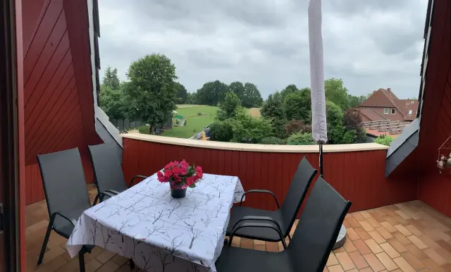 Südbalkon mit gedecktem Tisch, vier Stühlen und Sonnenschirm